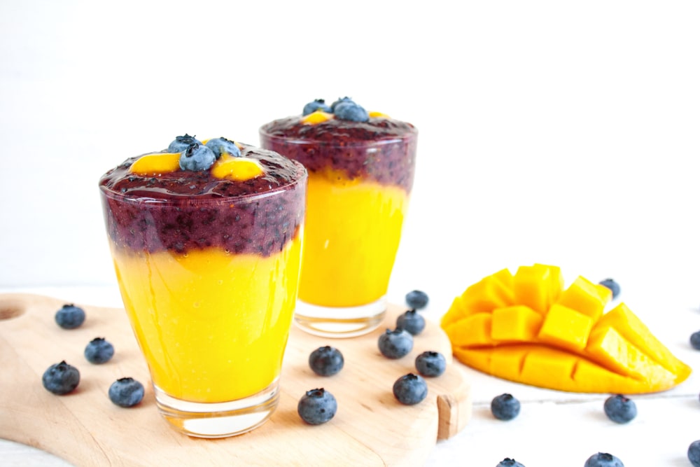 Smoothie z manga a červené řepy ve dvou skleničkách ozdobené borůvkami